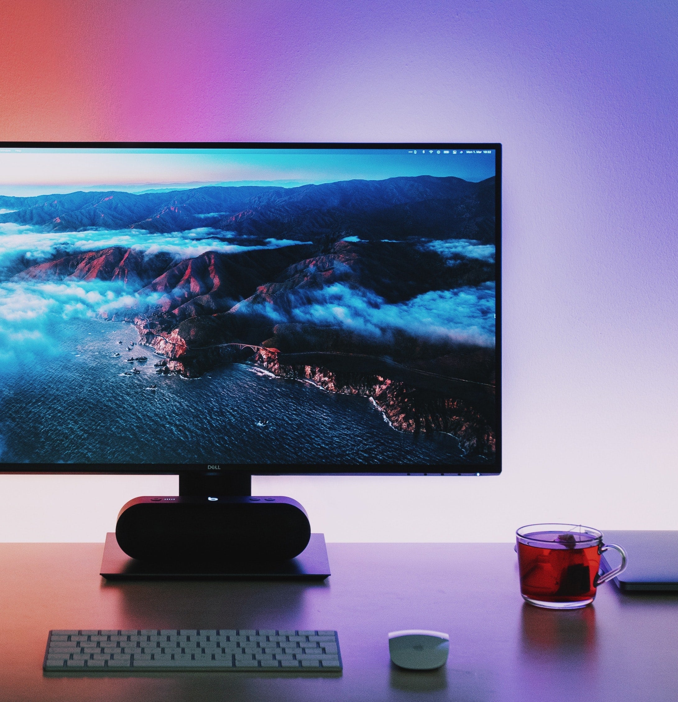 A High Definition monitor ,view of a mountainous landscape with a body of water, surrounded by a colourful gradient background