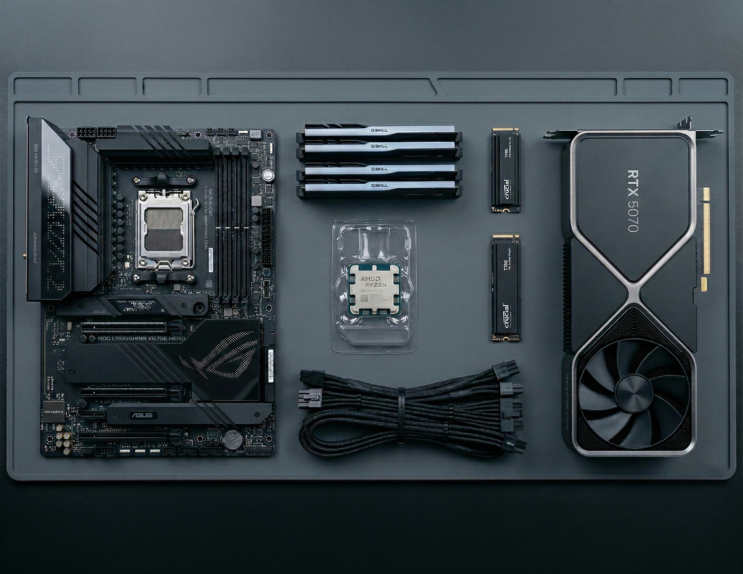 Gaming pc components are put on an gotraka assembly table, which includes an ASUS motherboard, AMD Ryzen processor, RTX 5070, data cables, G Skill ram and crucial SSDs