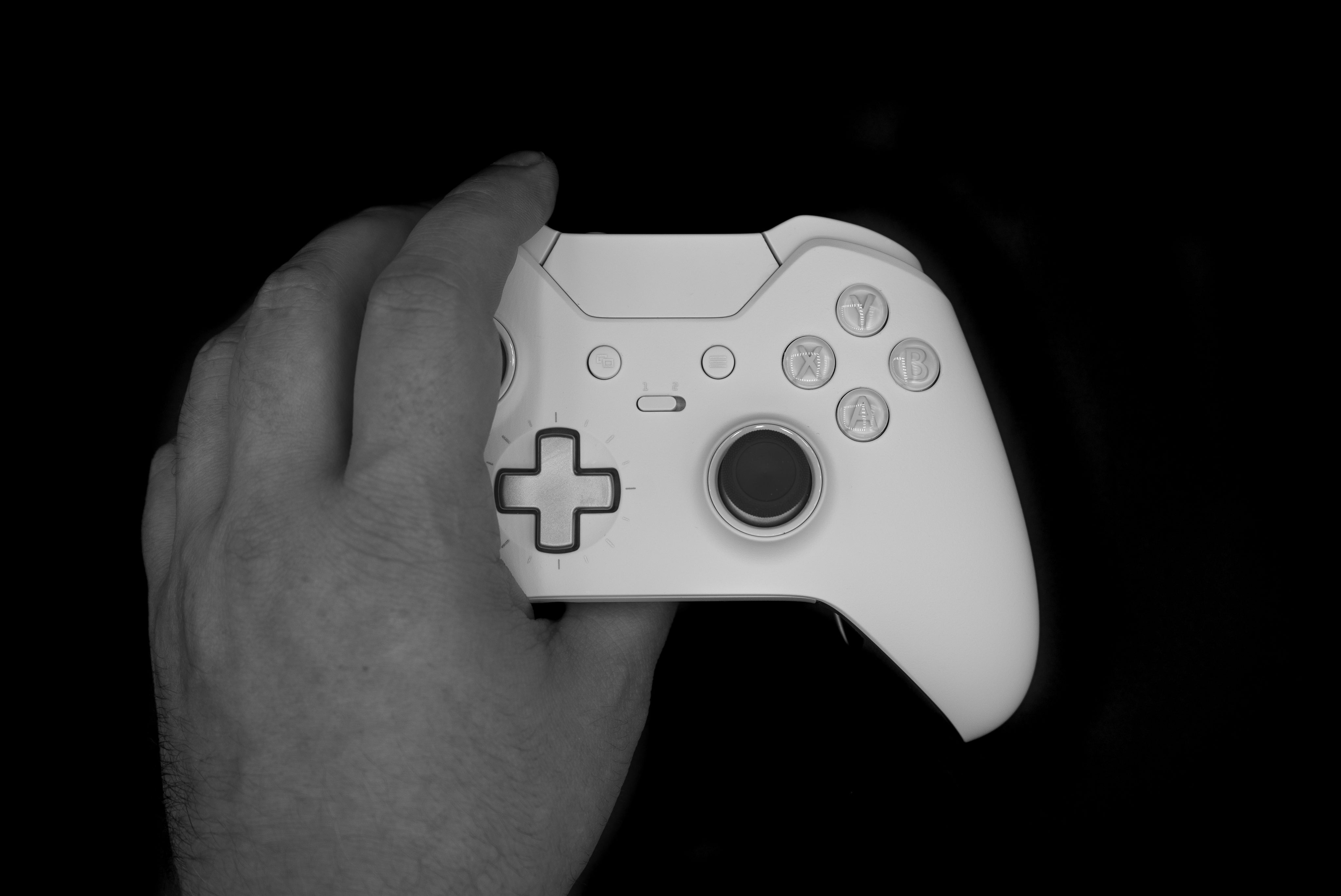 A white Xbox controller held in a hand against a dark background